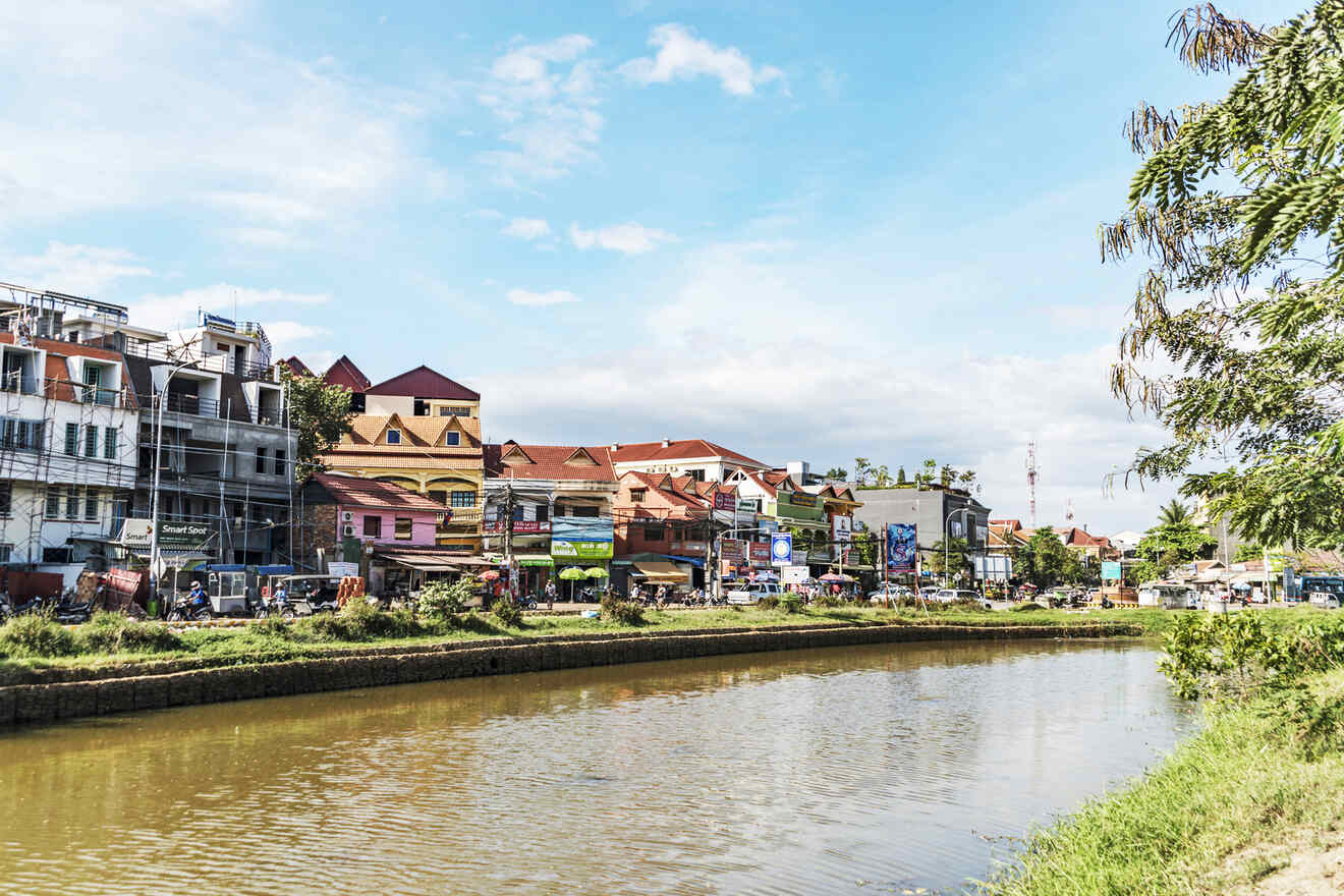 Colorful riverside buildings reflecting in the calm waters under a clear blue sky, with lush greenery adorning the riverbanks